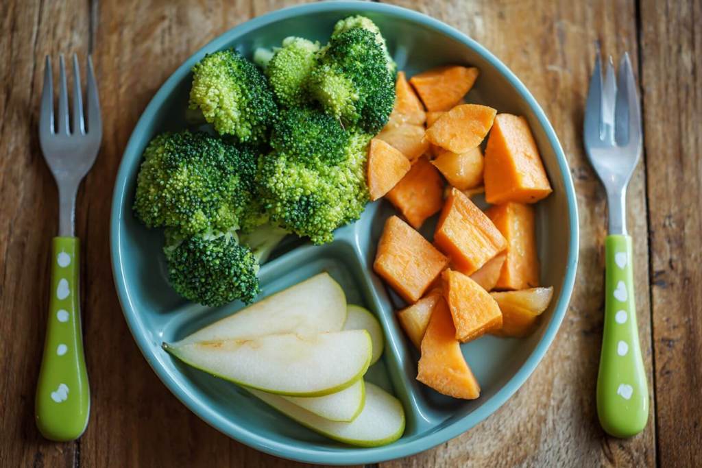 Plato de alimentación BLW con verduras y frutas cortadas en tiras para facilitar el agarre del bebé.
