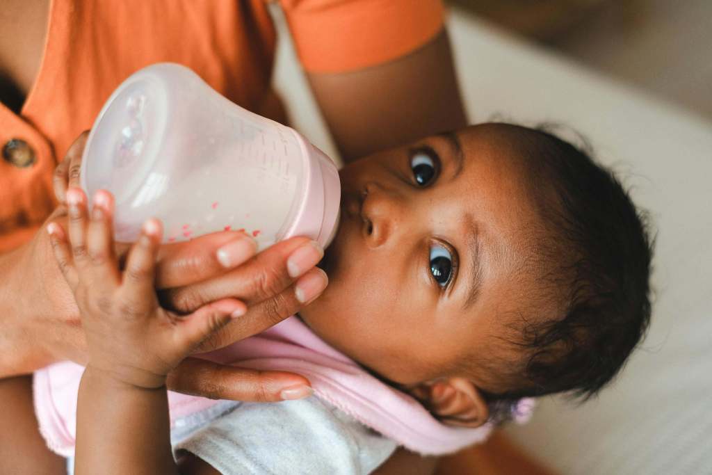 Un bebé se alimenta con un biberón de leche.