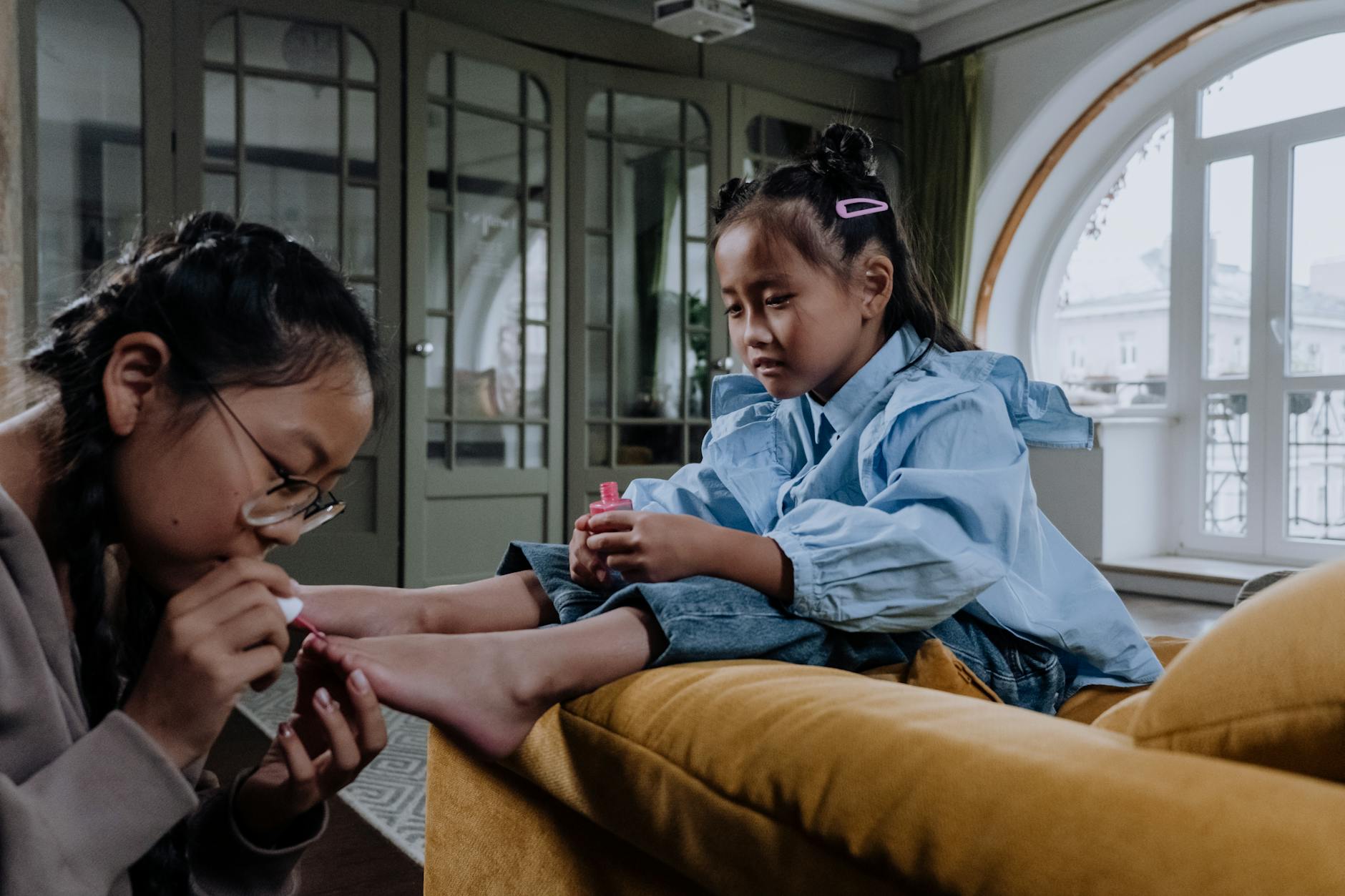 a young woman applying a nail polish on her sister s foot