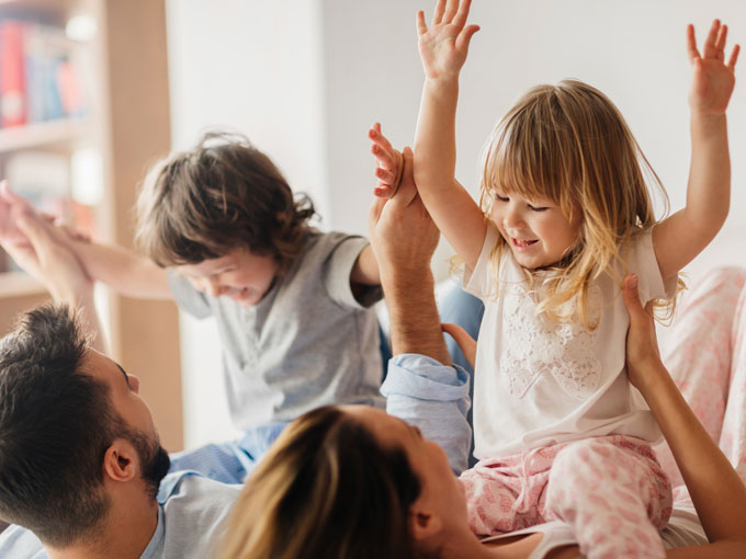 niños con padres jugando en la cama