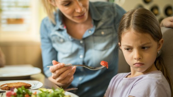 Niña enfadada comiendo