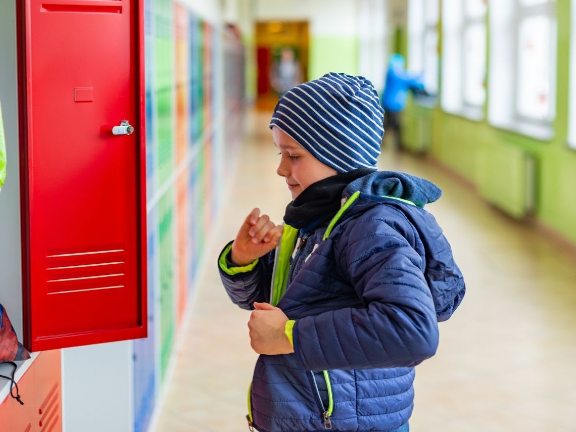 niño con abrigo en clase
