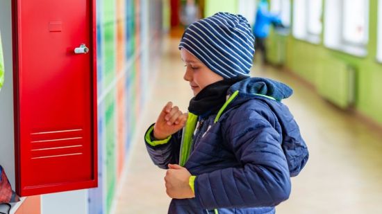 niño con abrigo en clase