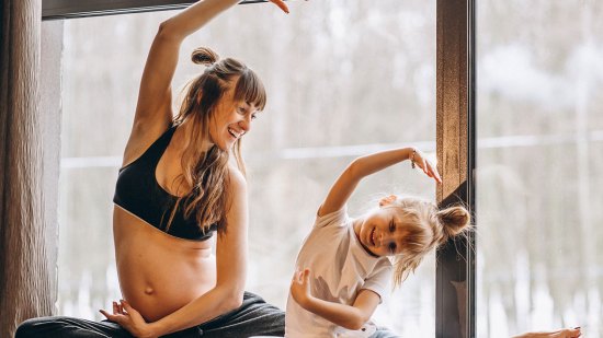 madre embarazada e hija practicando yoga