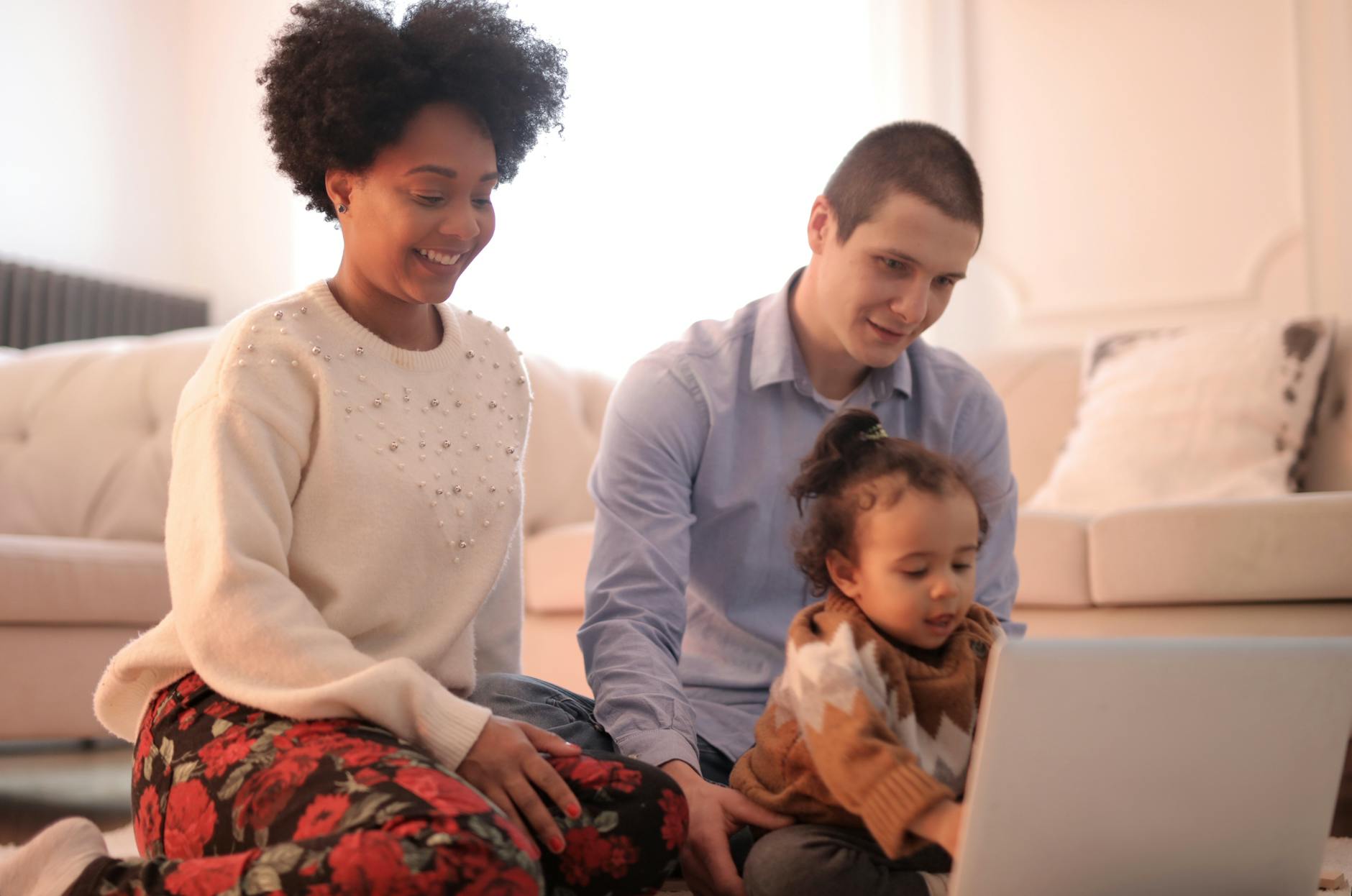 photo of family sitting on floor while using laptop