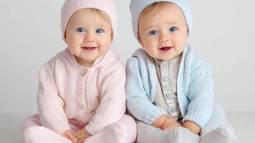 Bebé niña y bebé niño sentados juntos con ropa de punto rosa y azul