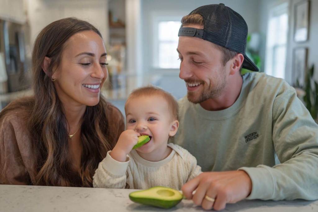 Bebé comiendo aguacate junto a sus padres.
