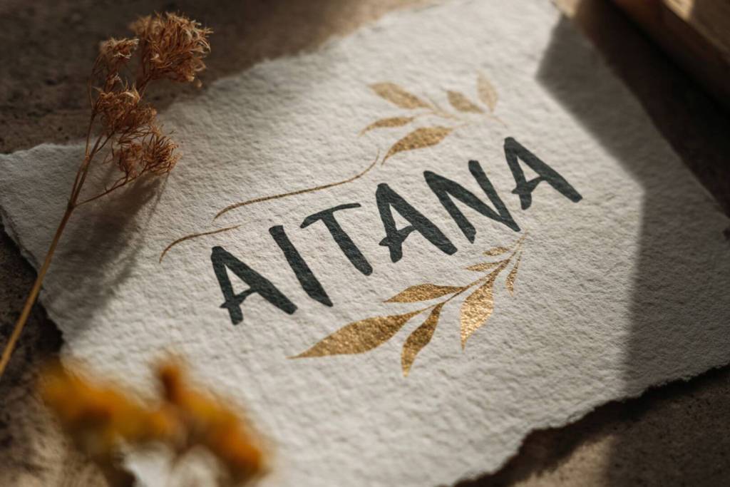 Nombre Aitana escrito en elegante lettering artístico sobre papel texturizado, con detalles dorados y flores secas