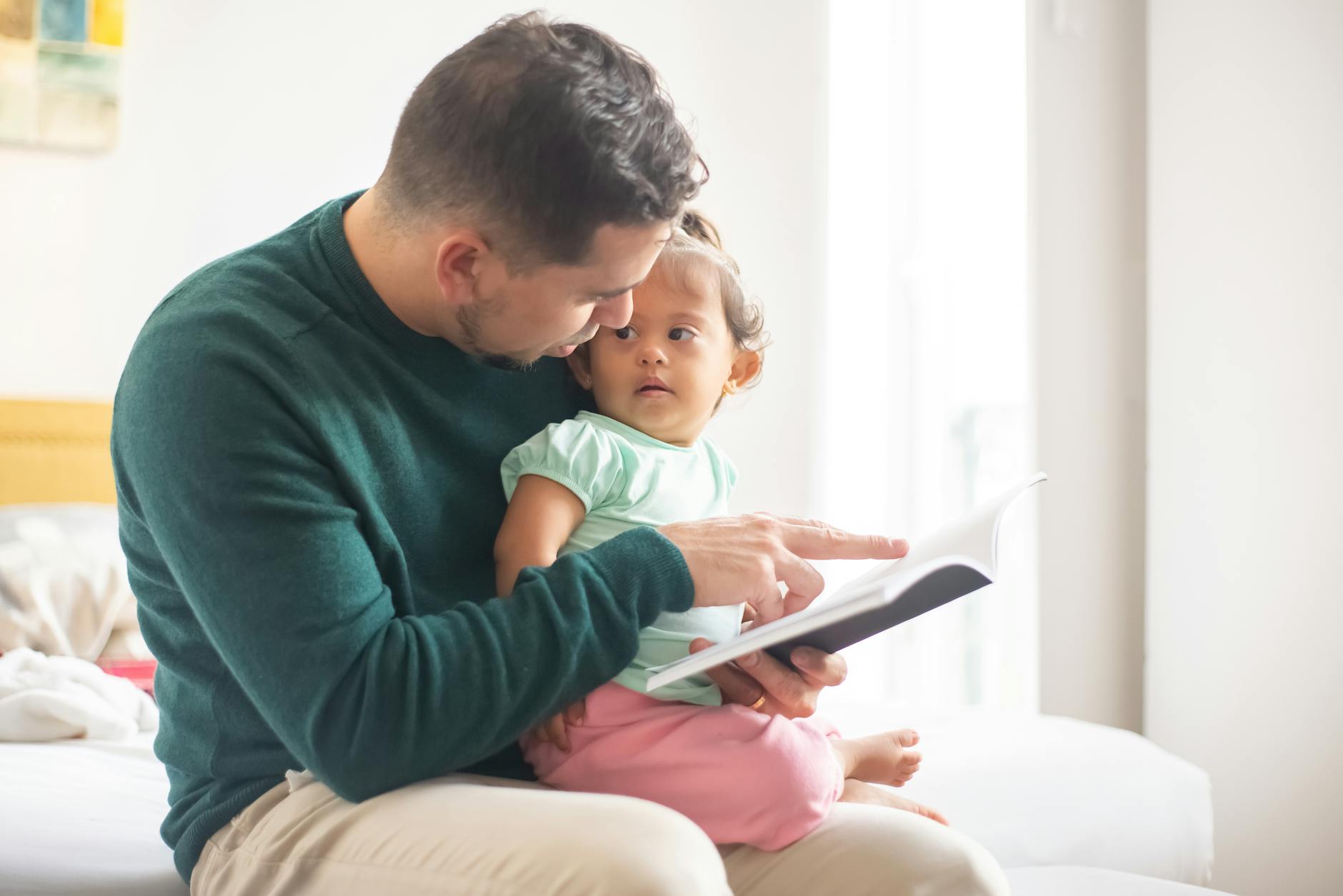 photograph of a father reading a book for her daughter