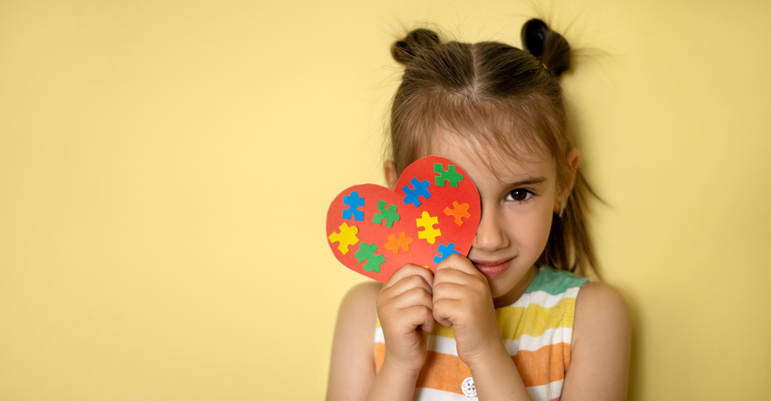 Niña con el corazón del rompecabezas del Autismo