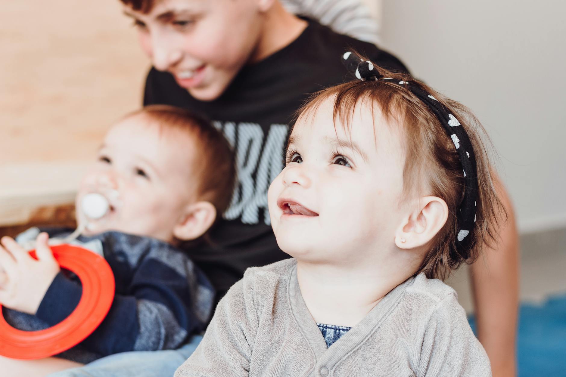 baby girl with headband sitting beside her siblings