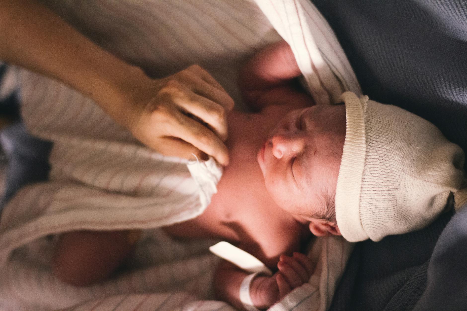 person covering infant with swaddling blanket