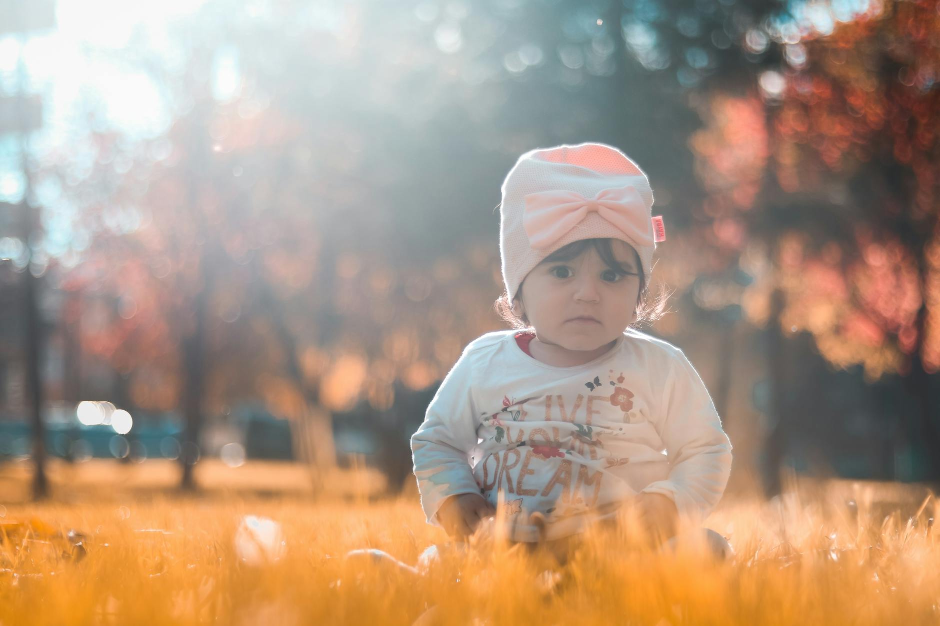 photo of toddler sitting on grass