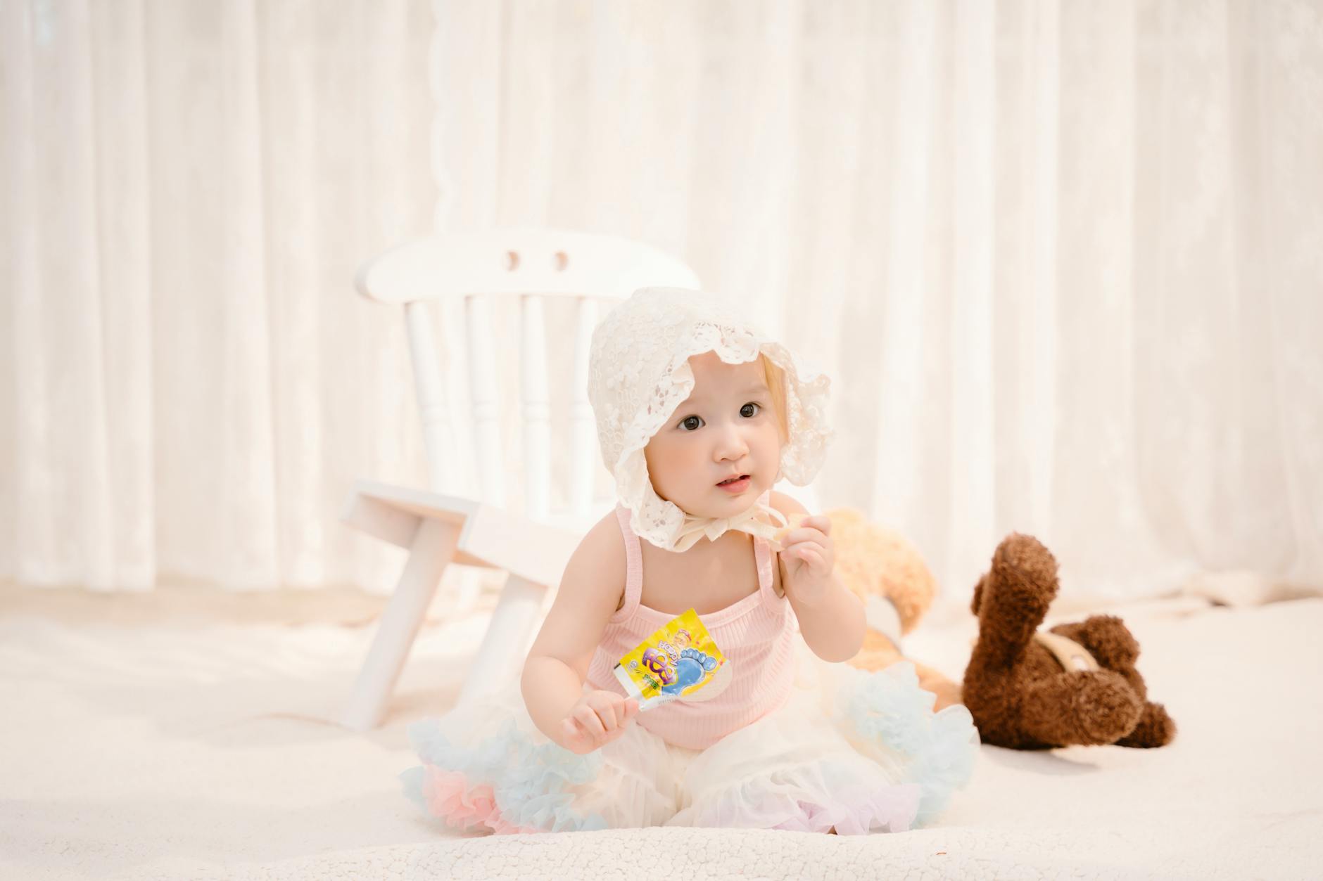 baby in bonnet hat holding lollipop