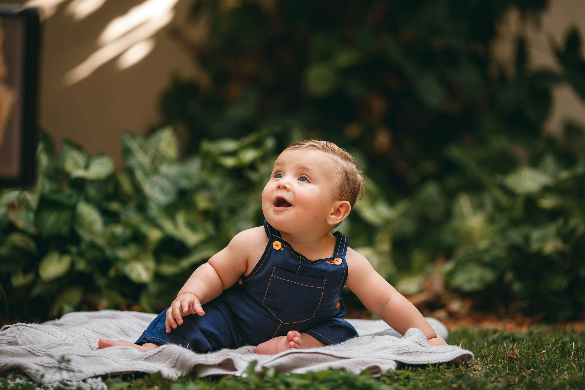 baby in jean overalls sitting on blanket
