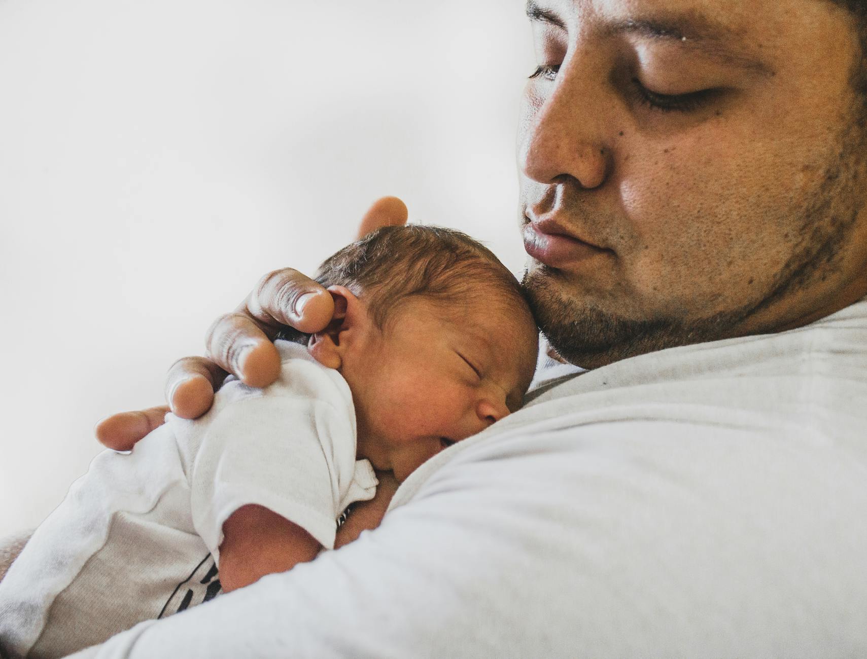 photo of father carrying newborn baby