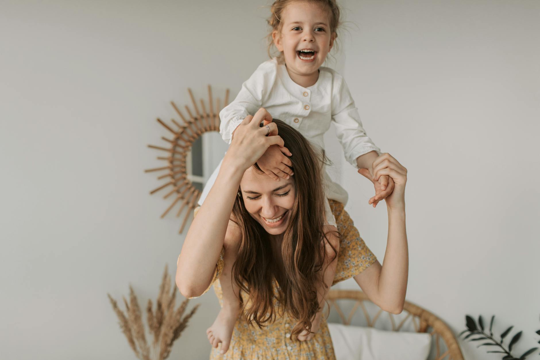 woman in yellow floral dress carrying baby girl over the shoulder