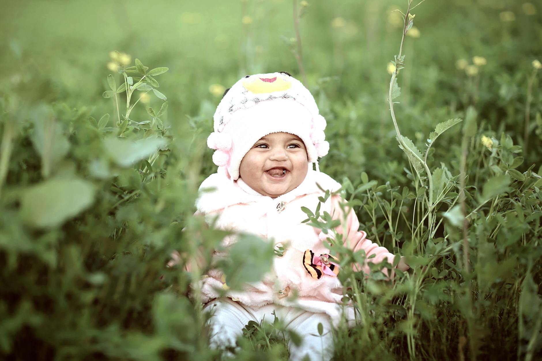 toddler wearing whit cap on green field