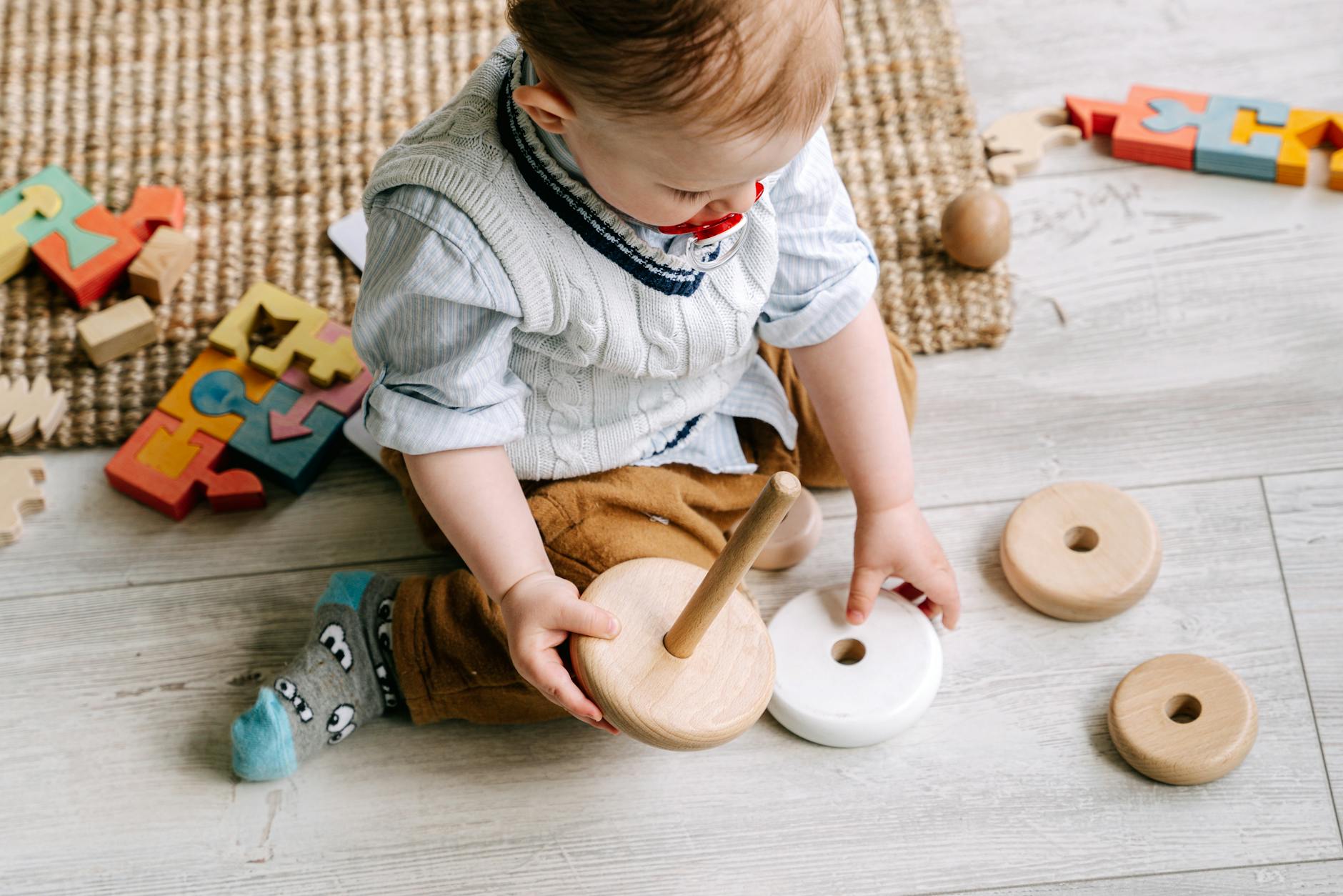 baby boy playing with wooden toy on floor