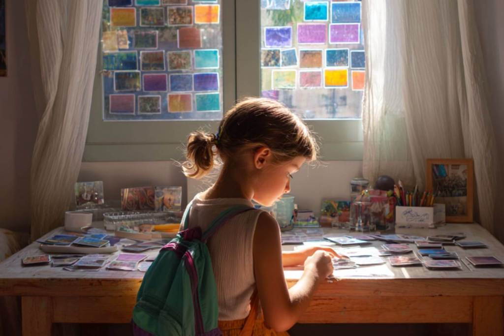 Niña con mochila observando y ordenando tarjetas de memoria en su escritorio.