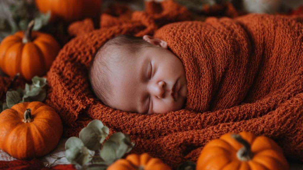 Un recién nacido envuelto en una manta con decoración de Halloween a su alrededor
