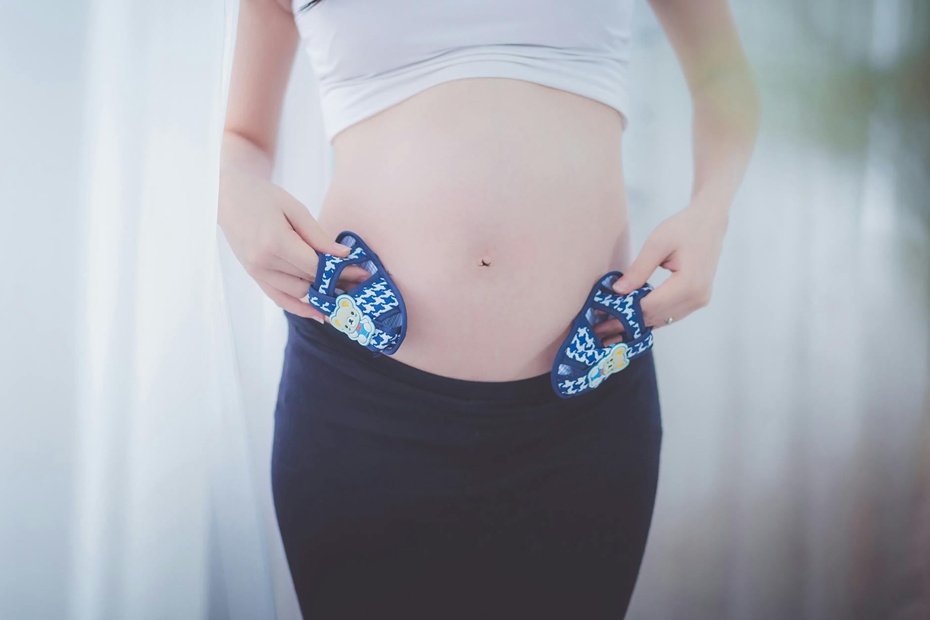 pregnant woman holding baby shoes in her tummy