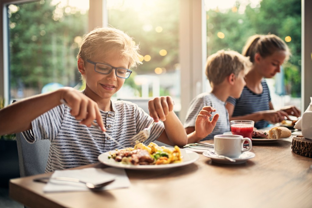 Un niño cena al lado de sus hermanos