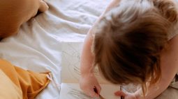 Niña coloreando mientras su madre trabaja a su lado