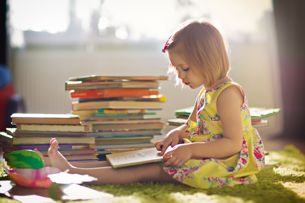 Niña en su habitación leyendo