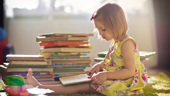 Niña en su habitación leyendo