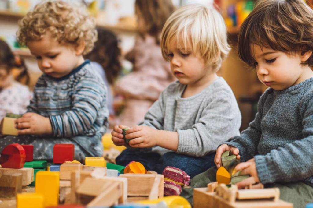 Niños pequeños jugando con bloques de construcción de colores en clase.