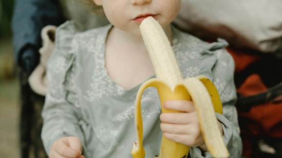 Niña comiendo un plátano