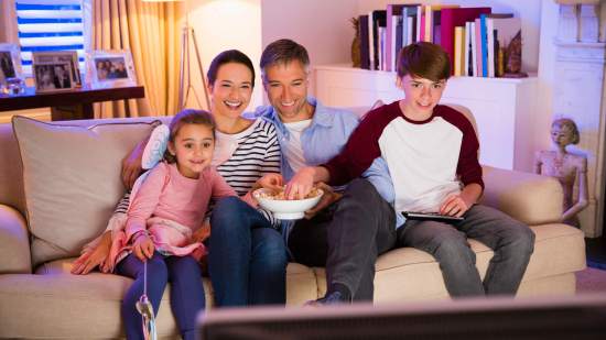 Familia comiendo palomitas y viendo la televisión