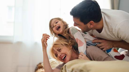 Familia divirtiéndose en la cama