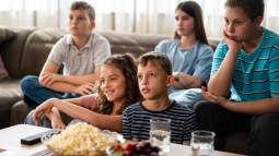 Grupo de adolescentes come ultraprocesados viendo la tele