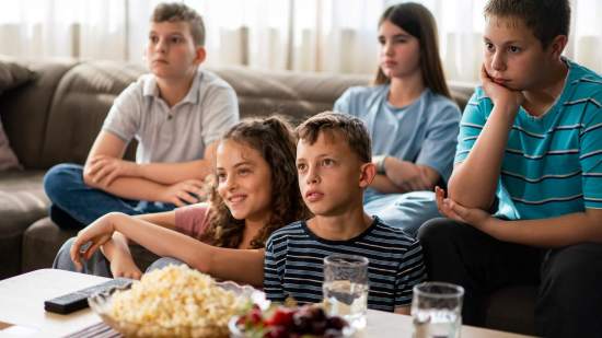 Grupo de adolescentes come ultraprocesados viendo la tele