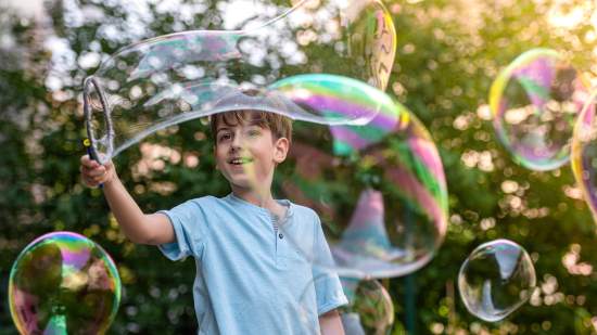 Un niño, haciendo pompas gigantes de jabón