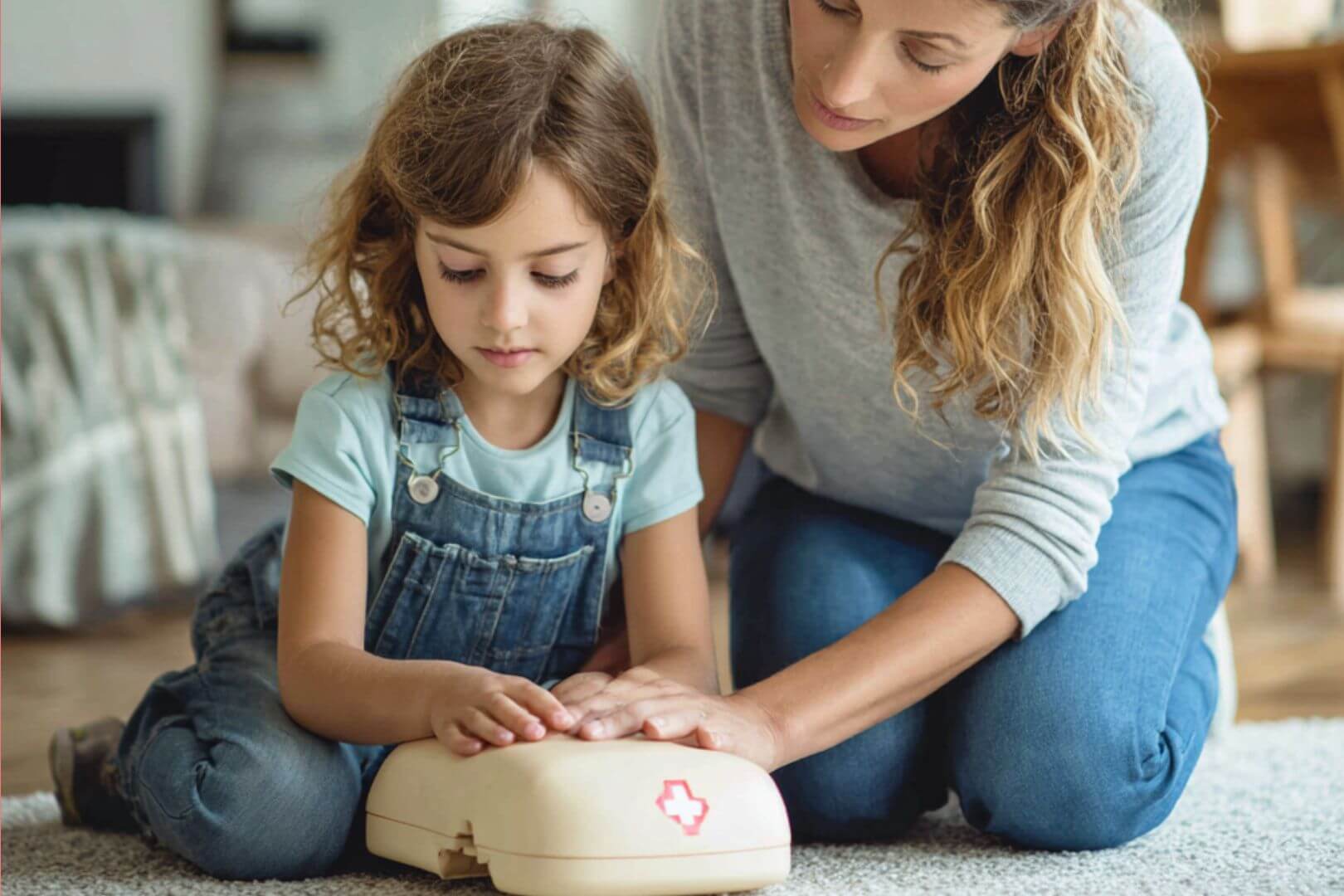 Niña aprendiendo maniobras de reanimación cardiopulmonar con la guía de su madre en casa.