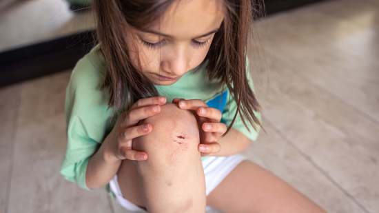 closeup-little-girl-holding-her-bruised-injured-damaged-knee-with-her-hands