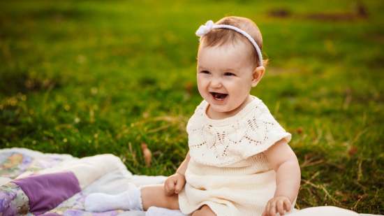 plump-little-girl-sits-white-blanket