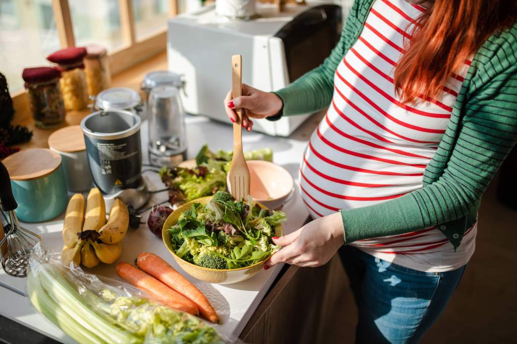 Una mujer embarazada se hace una ensalada