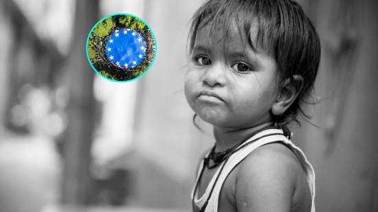 Una niña en situación de riesgo de pobreza. En la imagen de detalle, la bandera de la Unión Europea