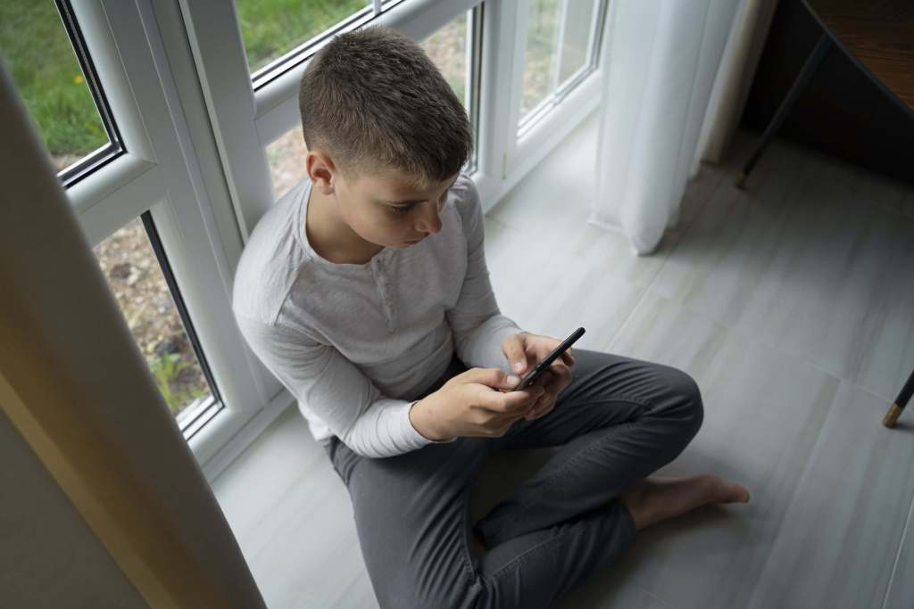 Un niño concentrado en su teléfono móvil