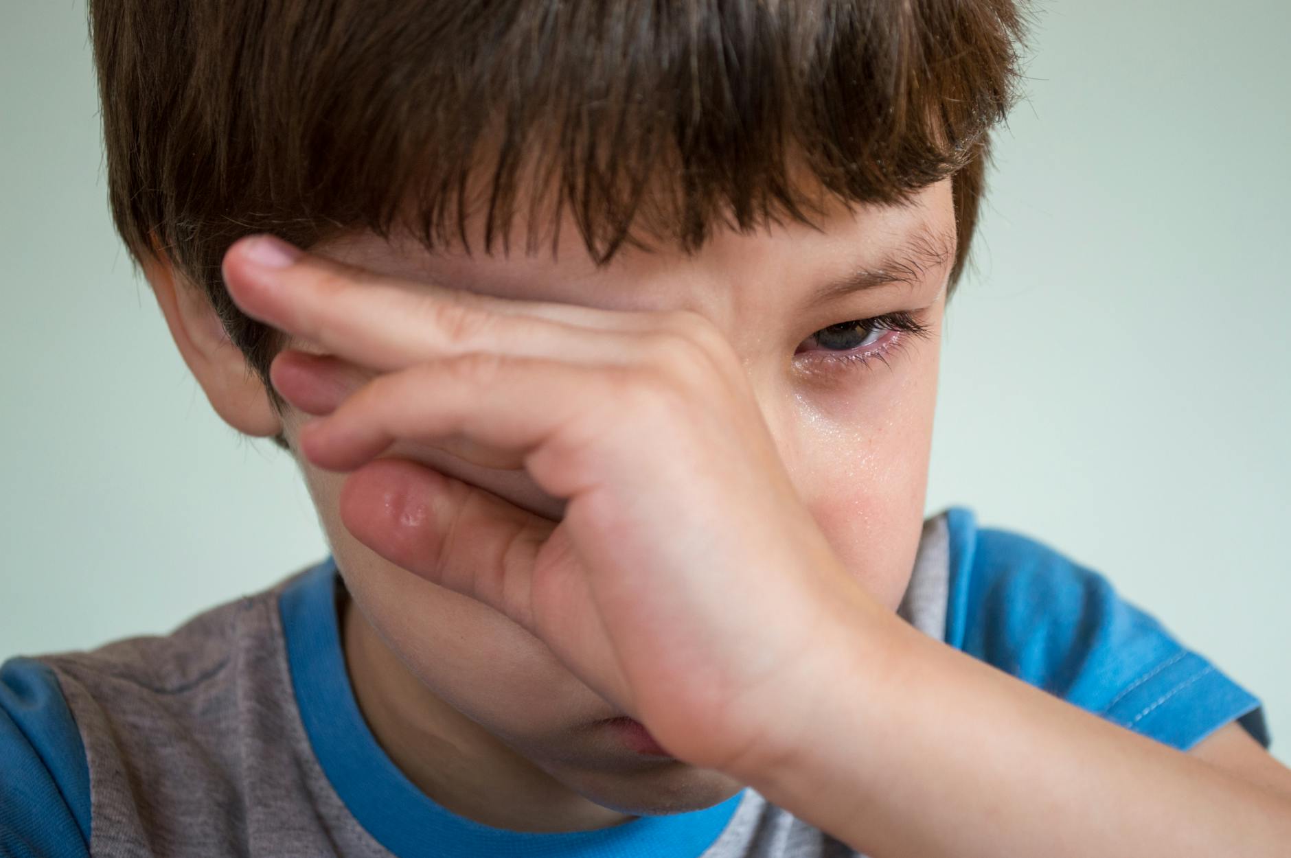 boy wiping tears from eye