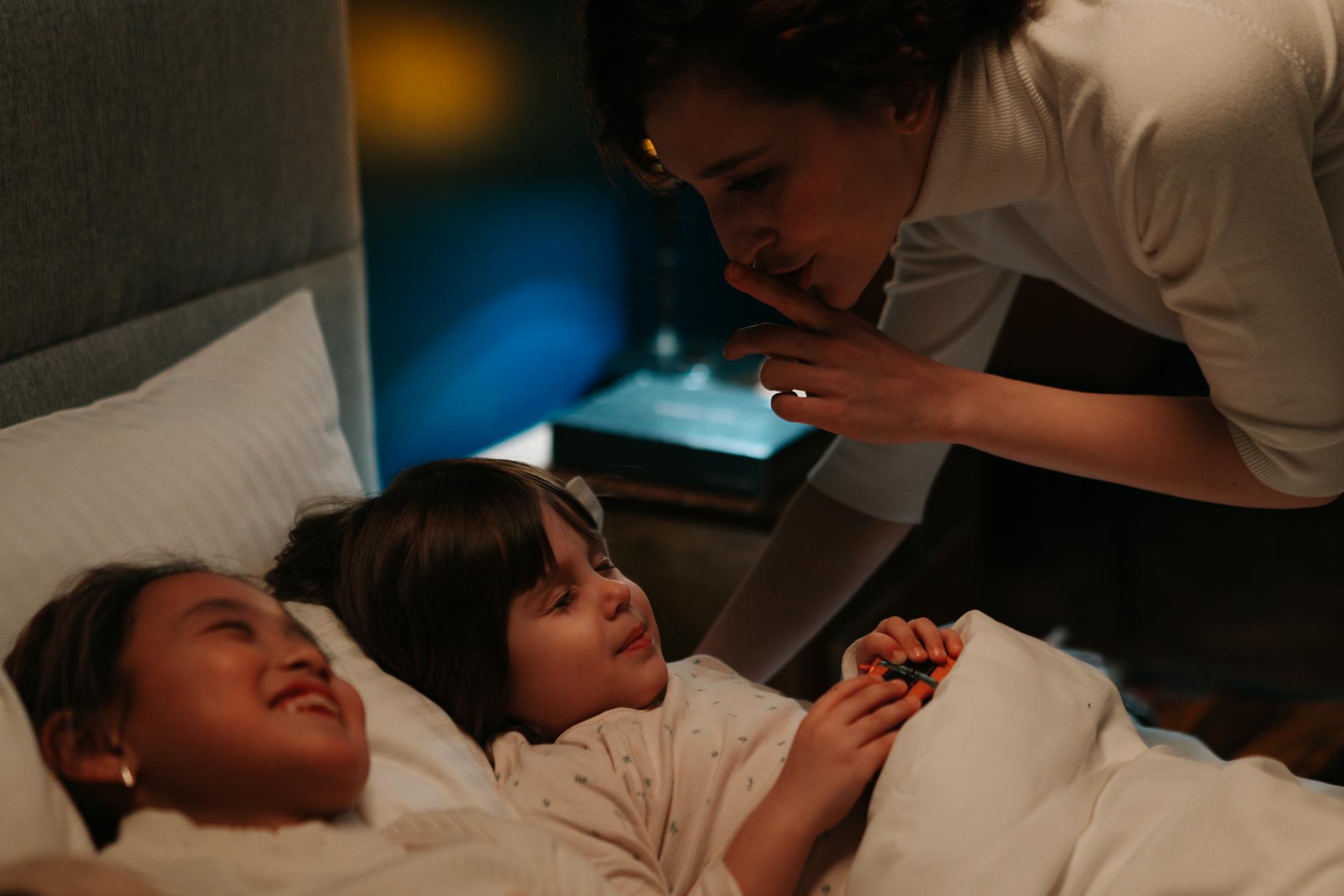 woman silencing two children to bed