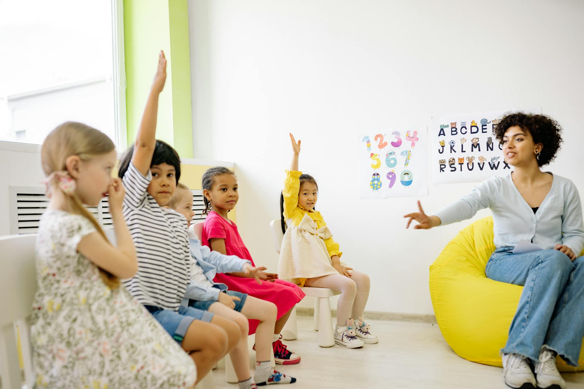 teacher giving lesson and children raising their hands