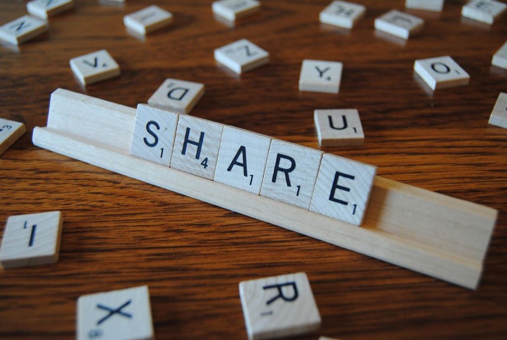La palabra "share" escrita con piezas de Scrabble