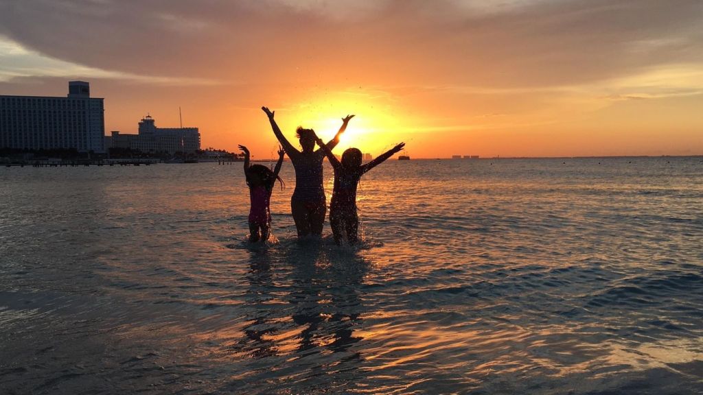 Tres personas en el mar en una puesta de sol