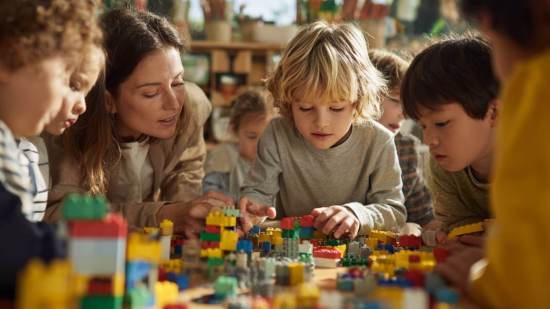 Una docente acompaña el aprendizaje de un grupo de niños mientras construyen con LEGO en el aula.