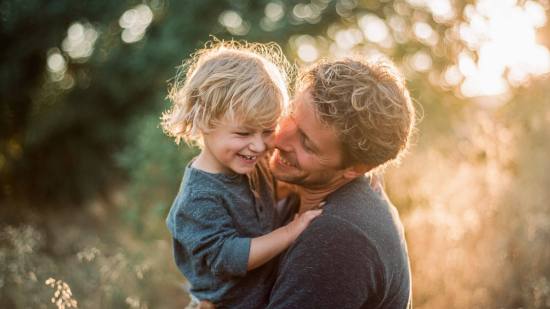Un padre ríe con su hijo al atardecer. Las primeras experiencias compartidas dejan huella en la infancia.